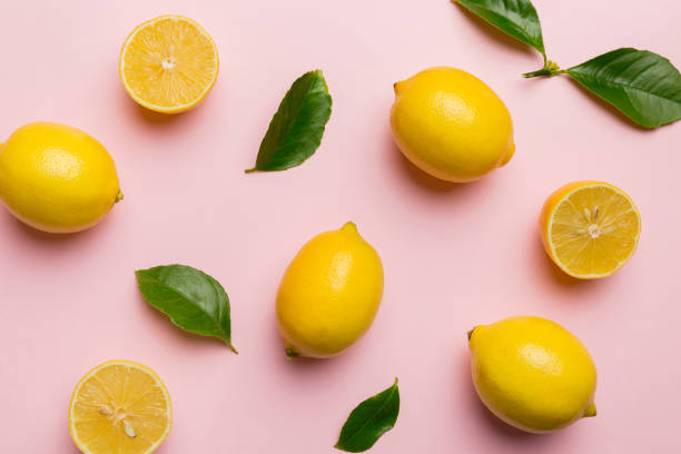 istock Many fresh ripe lemons with green leaves on colored background, top view, space for text 2117561686
