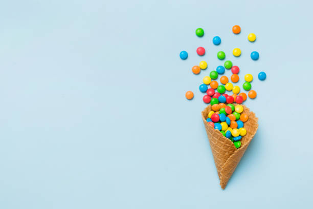 istock waffle cone full of assorted traditional candies falling out on colored background with copy space. Happy Holidays sale concept 2117562320
