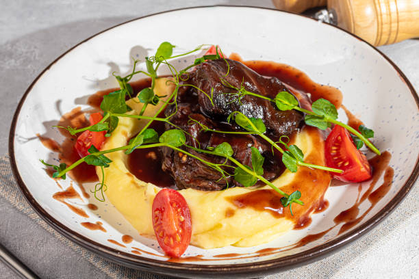 istock Mashed potatoes with beef in sweet and sour sauce, decorated with tomatoes and microgreens. 2117565607