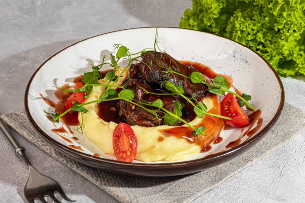istock Mashed potatoes with beef in sweet and sour sauce, decorated with tomatoes and microgreens. 2117565656