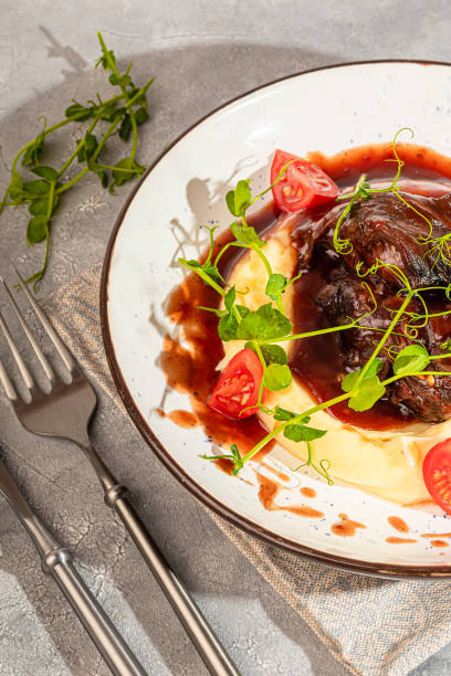 istock Mashed potatoes with beef in sweet and sour sauce, decorated with tomatoes and microgreens. 2117566695