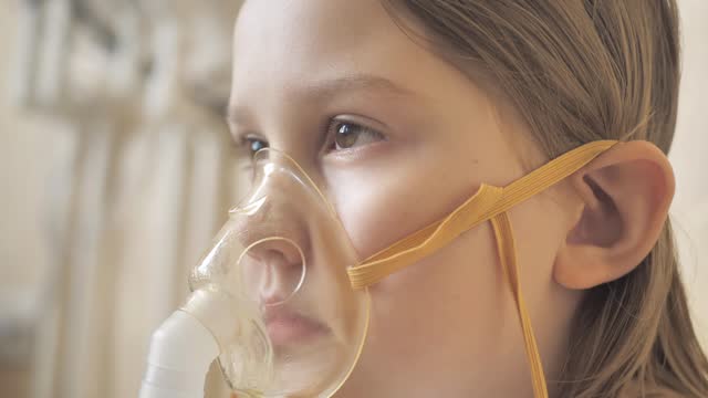 Portrait of a girl using a mask on her face to inhale the lungs using a nebulizer for a pulmonary disease. Treatment of bronchitis or pneumonia with covid 19. Cold and flu concept