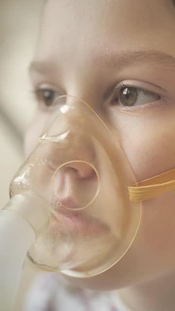 A vertical screen child uses an oxygen mask to inhale the respiratory tract using a nebulizer in the treatment of bronchi. Use of hormonal drugs for inhalation. Cold and flu concept.