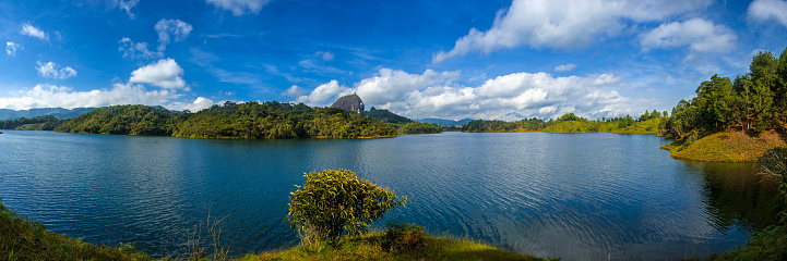 Behold the panoramic view of Guatape Reservoir, spanning the municipalities of Penol and Guatape in Antioquia, Colombia. In the background, the iconic Penol Rock stands tall, adding a touch of grandeur to this picturesque landscape.