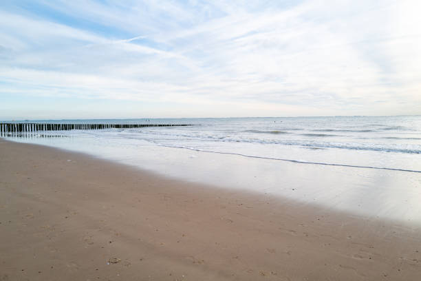 lonely beach with waves and sky in zeeland, the netherlands