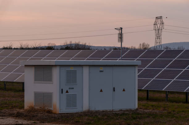 Transformer station in a solar power station at sunset with an electricity pylon and with cloudy sky.