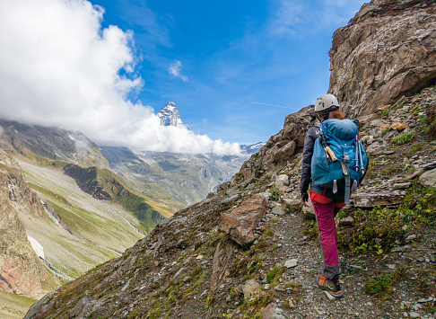 Breuil-Cervinia, Italy - 2 September 2023 - A view of Cervino mountain range of Alps in Valle d'Aosta region, with trekking paths, alpin lakes ed alpinistic way. Here in particular a girl alpinist with Cervino mount