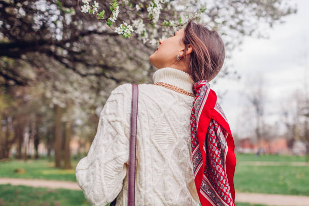 back view of stylish woman walking with red hair scarf in spring park. retro female fashion. headscarf for bun hairstyle - hair bun hairstyle women hair back photos et images de collection