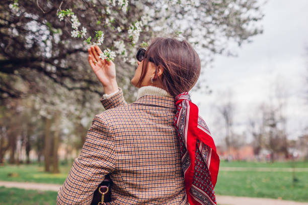 back view of stylish woman wearing red hair scarf in spring park. retro female fashion. headscarf for bun hairstyle - hair bun hairstyle women hair back photos et images de collection