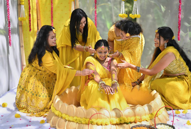 istock Bride's friends applying turmeric paste (Haldi) to the bride during Haldi ceremony 2117622041