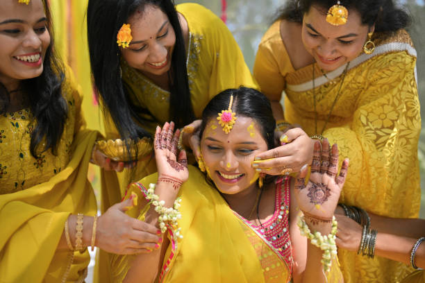 istock Close-up image of friends applying turmeric paste (Haldi ) to smiling bride during her haldi ceremony 2117623095