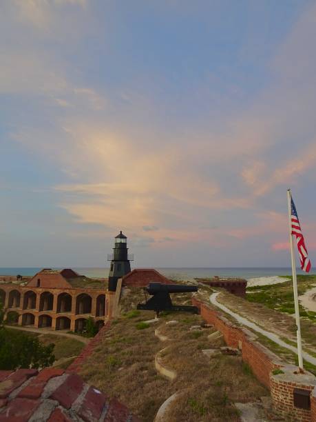 istock Sunset at Dry Tortugas with Lighthouse and American Flag 2117634700
