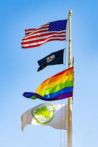 Christopher Park, Greenwich Village, Manhattan, New York, USA - March, 2024.  Flagpole at Christopher Park, which has played an important role in the history of the LGBT rights movement. The Stonewall uprising and other LGBT-related revolve around this Inn. This a flagpole containg a variety of flags including American flag, pride flag and 2 others of unknown origin.