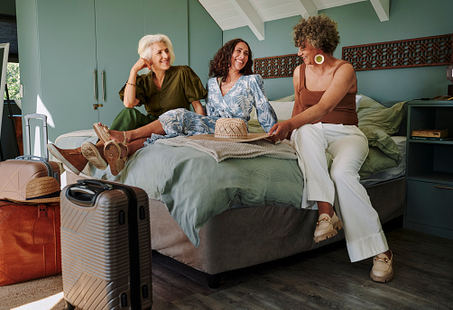 Group of mature female friends smiling and talking together in a bedroom after arriving at their vacation rental for a weekend getaway together