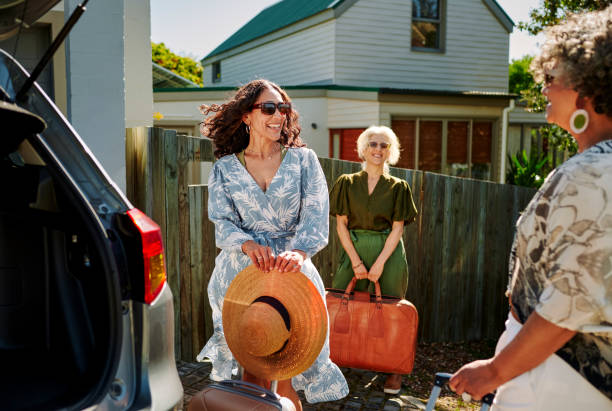 smiling mature women leaving for a road trip together in summer - active seniors enjoyment driveway vitality imagens e fotografias de stock