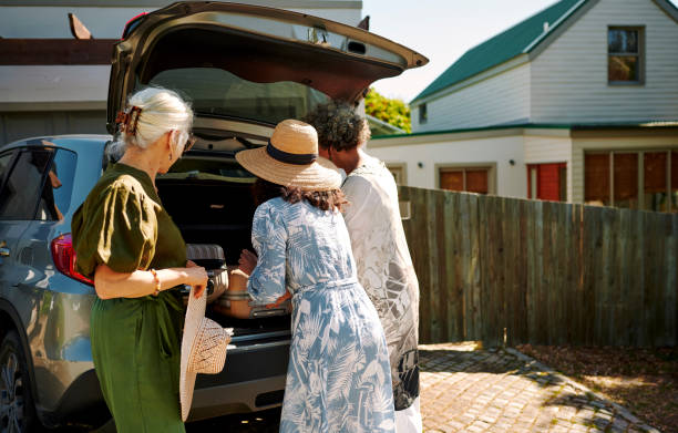mature women packing luggage into a car trunk for their weekend road trip - active seniors enjoyment driveway vitality imagens e fotografias de stock