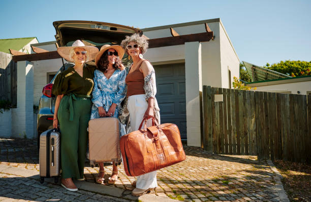 femmes mûres souriantes debout avec des bagages près de leur voiture avant un voyage en voiture - active seniors enjoyment driveway vitality photos et images de collection