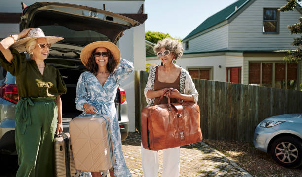 femmes d’âge mûr souriant près d’une voiture tout en se préparant pour un week-end en voiture - active seniors enjoyment driveway vitality photos et images de collection