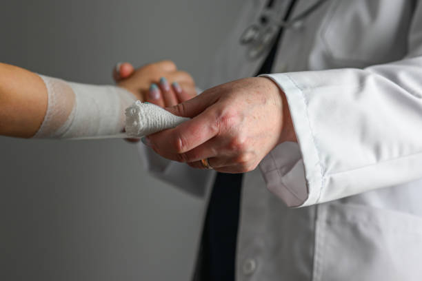 a doctor in a white coat with a stethoscope bandages the hand of a little girl - male nurse fotos stock-fotos und bilder