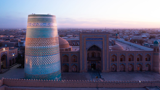 Uzbekistan Kalta Minor Minaret next to Muhammad Amin Khan Madrasa in the Old Town of Khiva. Drone Panorama in moody sunset twilight tothe famous iconic Kalta Minor Minaret and Muhammad Amin Khan Madrasa Iwan. Itchan Kala, Khiva - Chiva, Xorazm Region, Uzbekistan, Central Asia