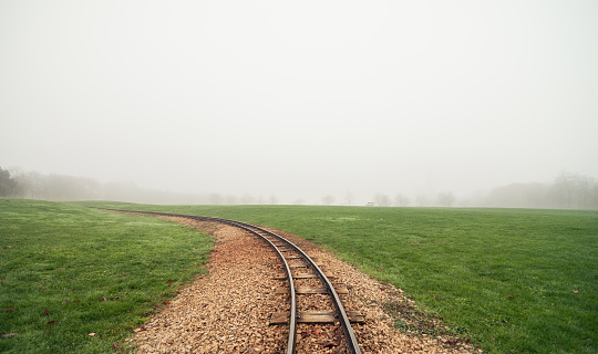 The track curves away from the viewer to the left, disappearing into the fog. Row of tree silhouettes in the background.