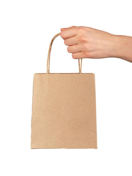 istock Hand holding, giving, presenting small gift bag, kraft package isolated on white 2117700630