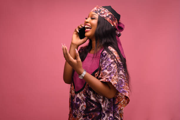 A joyful African American woman makes victory dance, raises head upwards and lifts up from joy, rejoicing triumph feeling winner, smiles broadly, on pink background.