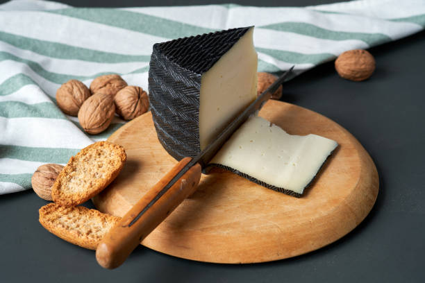 istock Cheese wedge on wooden board with sliced pieces and nuts 2117705914