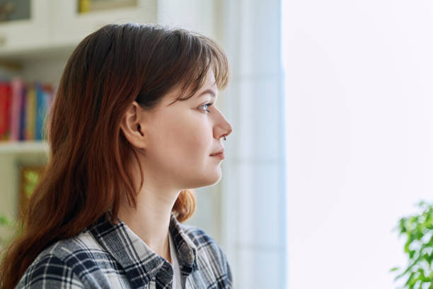istock Smiling young woman looking out the window, in home interior 2117749599