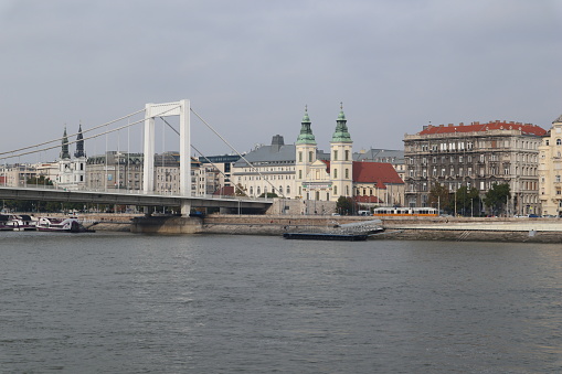 The white arch of Elisabeth bridge over the river Danube with a part of Pest, a church and a tram passing by visible, in Budapest, Hungary