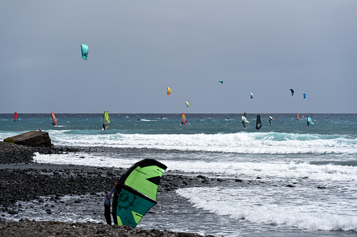 Two women doing kitesurfing and windsurfing on sea.