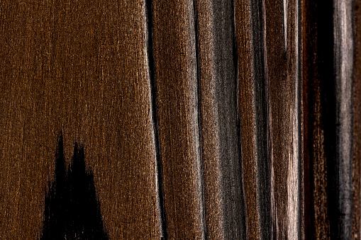 High angle view of a flat textured wooden board backgrounds.It burnt and black colored with fire skill.It is carbonization the surface. It has a beautiful nature and abstractive pattern. A close-up studio shooting shows details and lots of wood grain on the wood table. The piece of wood at the surface of the table also appears rich wooden material on it. The wood is black and pattern on the bottom. Flat lay style. Its high-resolution textured quality. The close-up gives a direct view on the table, showing cracks and knotholes in the wood.