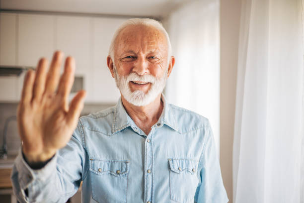 istock Elderly man smiling friendly at camera, waving hands hello, hi, greeting or goodbye 2117761740