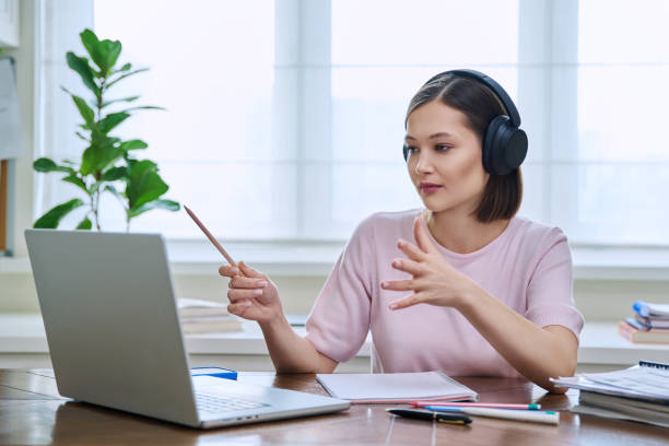 istock Young female college student in headphones studying using laptop computer for video chat 2117763562