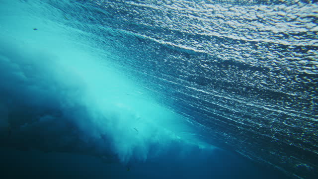 View from backside of strong ocean wave barrel spinning into curl with sparkling water pattern