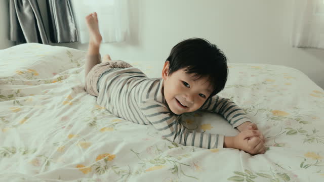 Cheerful Asian Boy Radiates Joy in Home Bedroom, Smiling with Innocence and Happiness.