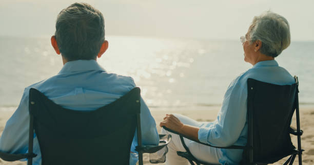istock Asian elderly cheerful couple has a deep conversation while sitting on a beach chair enjoying the sea view. A happy senior adult people enjoy the travel lifestyle after retirement. 2117808974