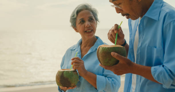 istock Asian elderly cheerful couple drinking coconut while walking on beach enjoying the sea view. A happy senior adult people enjoy the travel lifestyle after retirement. 2117809295