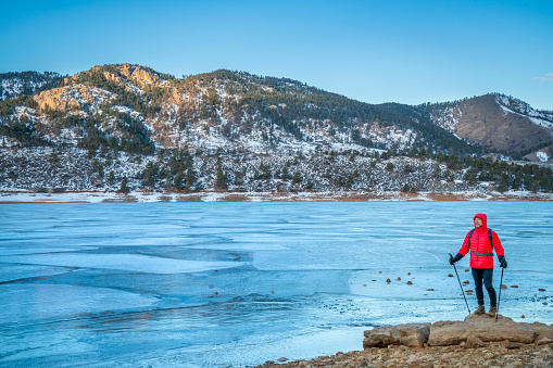 Self portrait of male hiker with trekking poles at a shore of frozen Horsetooth Reservoir near Fort Collins, Colorado - winter hiking concept
