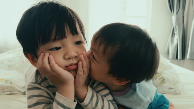 Authentic Joy: Asian Brothers Sharing Love and Laughter in Their Home Bedroom, Capturing the Essence of Sibling Bonding.