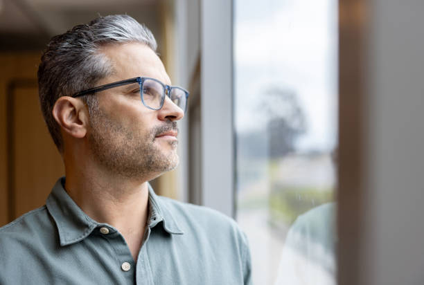 Thoughtful business man looking through the window at the office