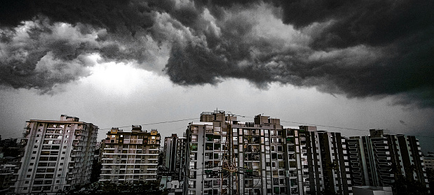 This image presents a dramatic scene of dark storm clouds looming over a cityscape. The contrast between the ominous power of nature and the human-made structures creates a compelling narrative. The image evokes a sense of anticipation and awe, highlighting the resilience of urban life amidst the unpredictable forces of nature