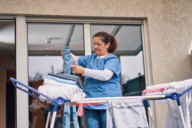 istock Domestic Cleaning Services -  Domestic Helper Hanging Laundry on a Clothes Rack 2117885072