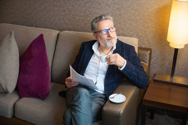 istock Concentrated entrepreneur with papers drinking tea from cup and looking away 2117887782