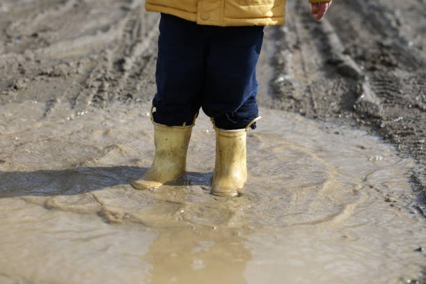 istock Little boy playing in mud water 2117902764