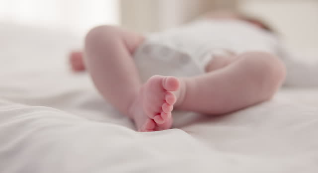 Sleeping, family and feet of baby on bed for child care, dreaming and relax in nursery. Adorable, cute and closeup of toes of innocent newborn infant for health, wellness and development at home