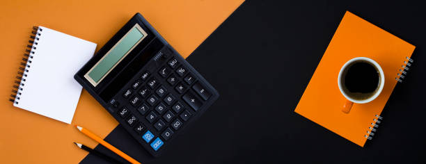 istock Calculator, pencil, notebook and coffee cup on the black background. Copy space. Top view. 2117943628