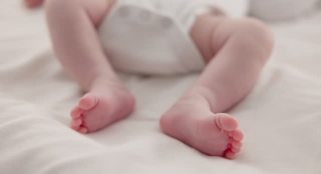 Sleeping, adorable and feet of baby on bed for child care, dreaming and relax in nursery. Family, cute and closeup of toes of innocent newborn infant for health, wellness and development at home