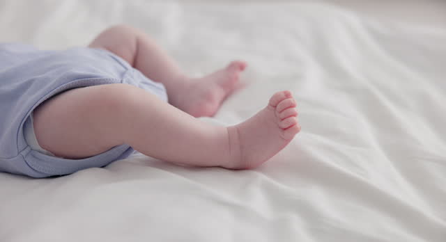 Adorable, family and feet of baby on bed for child care, relax and resting in nursery. Innocent, cute and closeup of toes of innocent newborn infant for health, wellness and development at home