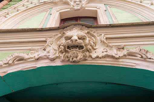 St. Petersburg, Russia, February 10, 2024. Interesting molding on the facade of an old house, grinning lion s face above the gate, artwork, architectural details, signs and symbols, interesting architectural background, daylight, stock photo.